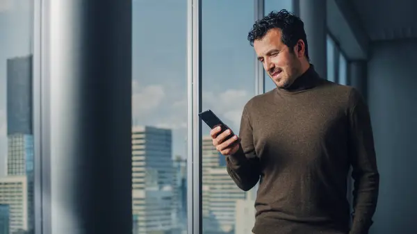Ajattelevainen Arabiliikemies Käyttää Älypuhelinta Seisoo Toimistossa Katse Ulos Ikkunasta Big — kuvapankkivalokuva