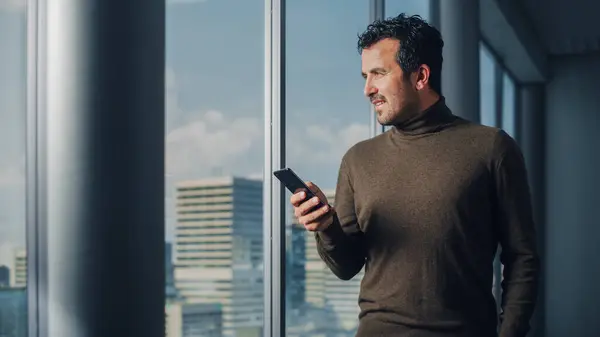 Ajattelevainen Arabiliikemies Käyttää Älypuhelinta Seisoo Toimistossa Katse Ulos Ikkunasta Big — kuvapankkivalokuva