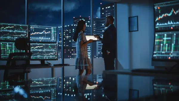 金融分析师在深夜工作时与投资银行交谈 在平板电脑上讨论实时股票图表数据 商人在经纪代理市办公室开了一个会 — 图库照片