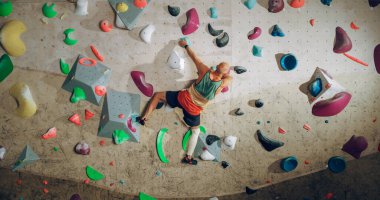 Güçlü Deneyimli Kaya Tırmanışçısı Spor Salonunda Tek başına Bouldering Wall 'a tırmanıyor. Kapalı Spor Salonu 'nda egzersiz yapan, Sağlıklı Yaşam Tarzı Eğitimi İçin Ekstrem Spor Yapan Adam. Arkadan çekim.