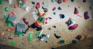 Güçlü Deneyimli Kaya Tırmanışçısı Spor Salonunda Tek başına Bouldering Wall 'a tırmanıyor. Kapalı Spor Salonu 'nda egzersiz yapan, Sağlıklı Yaşam Tarzı Eğitimi İçin Ekstrem Spor Yapan Adam. Arkadan çekim.