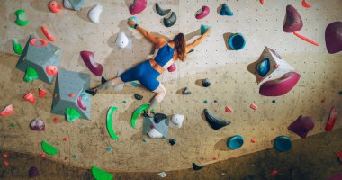 Sporcu Kadın Kaya Tırmanışçısı Spor Salonunda Tek başına Bouldering Wall 'a tırmanıyor. Kapalı Spor Salonu 'nda Kadın Egzersizleri Sağlıklı Yaşam Tarzı Eğitimi İçin Aşırı Spor Yapıyor. Arkadan çekim.