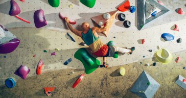 Güçlü Deneyimli Kaya Tırmanışçısı Spor Salonunda Tek başına Bouldering Wall 'a tırmanıyor. Kapalı Spor Salonu 'nda egzersiz yapan, Sağlıklı Yaşam Tarzı Eğitimi İçin Ekstrem Spor Yapan Adam. Arkadan çekim.