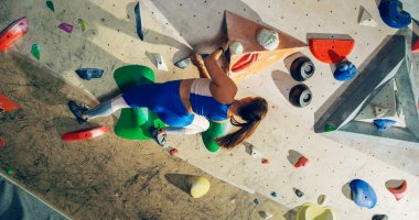 Sporcu Kadın Kaya Tırmanışçısı Spor Salonunda Tek başına Bouldering Wall 'a tırmanıyor. Kapalı Spor Salonu 'nda Kadın Egzersizleri Sağlıklı Yaşam Tarzı Eğitimi İçin Aşırı Spor Yapıyor. Arkadan çekim.