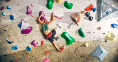 Güçlü Deneyimli Kaya Tırmanışçısı Spor Salonunda Tek başına Bouldering Wall 'a tırmanıyor. Kapalı Spor Salonu 'nda egzersiz yapan, Sağlıklı Yaşam Tarzı Eğitimi İçin Ekstrem Spor Yapan Adam. Arkadan çekim.