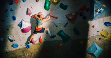 Güçlü Deneyimli Kaya Tırmanışçısı Spor Salonunda Tek başına Bouldering Wall 'a tırmanıyor. Kapalı Spor Salonu 'nda egzersiz yapan, Sağlıklı Yaşam Tarzı Eğitimi İçin Ekstrem Spor Yapan Adam. Arkadan çekim.