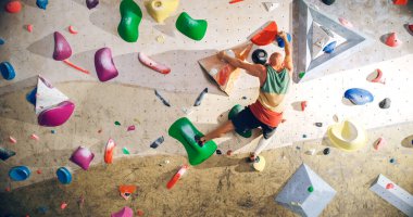 Güçlü Deneyimli Kaya Tırmanışçısı Spor Salonunda Tek başına Bouldering Wall 'a tırmanıyor. Kapalı Spor Salonu 'nda egzersiz yapan, Sağlıklı Yaşam Tarzı Eğitimi İçin Ekstrem Spor Yapan Adam. Arkadan çekim.