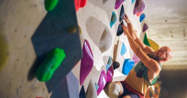 Güçlü Deneyimli Kaya Tırmanışı Spor Salonunda Tek başına Bouldering Wall 'a tırmanıyor. Kapalı Spor Salonu 'nda egzersiz yapan, Sağlıklı Yaşam Tarzı Eğitimi İçin Ekstrem Spor Yapan Adam. Portreyi Kapat