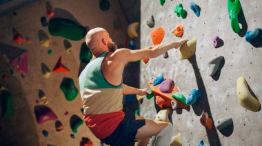Güçlü Deneyimli Kaya Tırmanışı Spor Salonunda Tek başına Bouldering Wall 'a tırmanıyor. Kapalı Spor Salonu 'nda egzersiz yapan, Sağlıklı Eğitimi İçin Olağanüstü Spor Yapan Adam. Yaşam Tarzı Portresi.