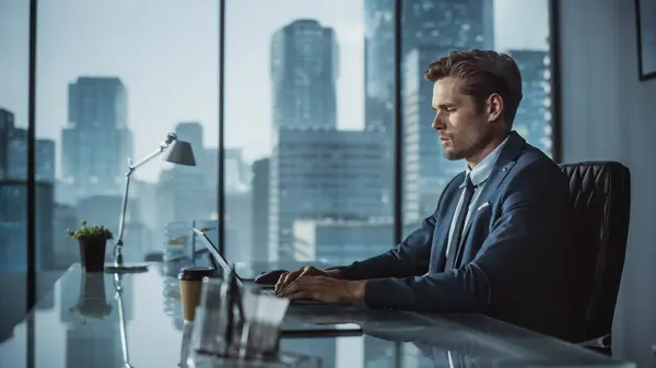 Itsevarma Liikemies Puvussa Istuu Työpöydän Ääressä Modernissa Toimistossa Kannettavan Tietokoneen — kuvapankkivalokuva