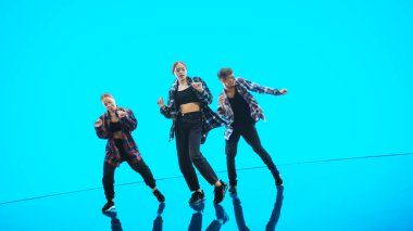 Üç Profesyonel Dansçı, Turkuaz ve Mavi Renkli Büyük Dijital Led Duvarın Önünde Hip Hop Dans Gösterisi Yapıyor