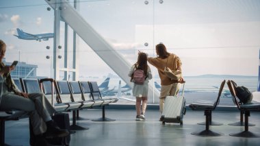 Havaalanı Terminali: Güzel Anne ve Şirin Küçük Kızı Gelen ve Giden Uçaklar İçin Pencereden Dışarı Bakıyorlar, Seyahat Uçuşlarını Bekliyorlar