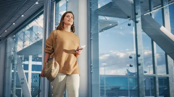 空港ターミナル 美しい笑顔の女性がチケットを保持し 彼女の飛行機が彼女を待っているゲートにビッグエアラインハブを通って歩きます ハッピー コーカサス — ストック写真