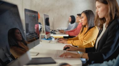 Çeşitli etnik çeşitlilikteki Kadın ve Erkek Öğrenciler Kolej Odasında Oturarak Bilgisayar Bilimi Öğreniyor. Genç Bilginler Bilgi Teknolojisi okuyor