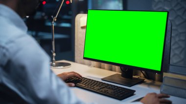Chroma Key Green Screen Mock Up ekranıyla Masaüstü Bilgisayarı üzerinde çalışan bir İşadamının Kapanışı. Dijital Projeleri Yöneten Erkek Yönetici