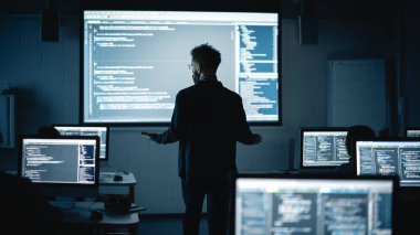 Karanlık Üniversite Odasında Çok Irklı Kadın ve Erkek Öğrencilere Bilgisayar Bilimleri Dersi Veren Öğretmen. Slayt Gösterisi Bununla Projeleniyor