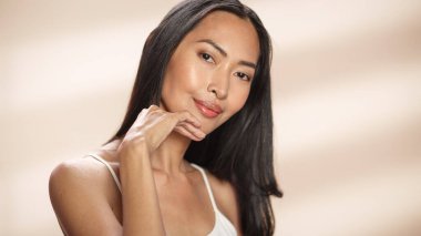 Kadın Güzellik Portresi. Güzel Asyalı Esmer Kadın, Gülümseyen, Yüzüne Doğal, Sağlıklı Ciltle Dokunan. Sağlık ve Cilt Bakımı