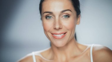 Güzel beyaz kadın kameraya bakıyor, gülümsüyor. Kadın güzelliğinin, kendine olan saygısının ve sağlığının tadını çıkarıyor. Doğal Kozmetik Cilt Ürünleri