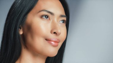 Güzel Asyalı Kadın yukarı bakıyor. Kadın, güzelliğinin, kendine olan saygısının ve sağlığının tadını çıkarıyor. Doğal Kozmetik Teni Ürünleri. Yakın plan Portre