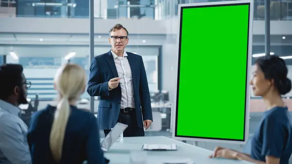 公司运营经理为一组经济学家举行会议 成年男性使用垂直绿色屏幕造型的数码白板 — 图库照片