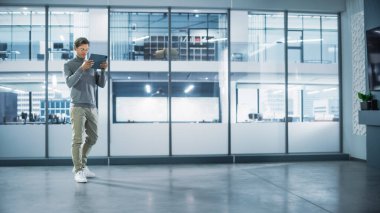 Yakışıklı İç Tasarımcı Boş Modern Ofiste Duruyor ve Tablet Bilgisayar 'da Artırılmış Gerçeklik Yazılımı ile haritasını çıkarıyor. Mimar