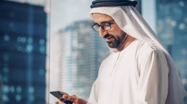 Modern Ofisinde Bekleyen Geleneksel Beyaz Üniformalı Başarılı Müslüman İş Adamı Gökdelenli Akıllı Telefon Kullanıyor. Başarılı.