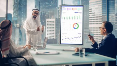 Emirati Businessman Holds Meeting Presentation for International Business Partners. Manager Uses Whiteboard with Growth Analysis, Charts, Statistics clipart