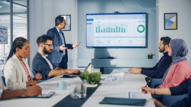 Çoklu Etnik Ofis Konferans Odası. Parlak Hintli Erkek CEO, TV Bilgileri kullanarak Çok Etnik Yönetici Grubunun Sunumunu yapıyor.