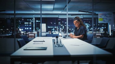 Mutlu Yetişkin Afrikalı Afrika kökenli, siyah elbiseli, konferans odasında gece yarısı laptoplu iletişim bilgisayarı üzerinde çalışan Amerikalı bir kadın. Başarılı.