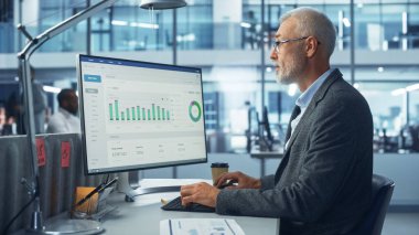 Şirket Ofisi: Büyük Veri İstatistikleri Grafikleri ile Kıdemli Bilgi İşlem Uzmanı Masaüstü Bilgisayarını Kullanıyor. Gülümseyen Yaratıcı Yazılım Mühendisi eCommerce üzerine çalışıyor
