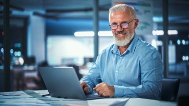 Laptop Bilgisayar 'da Başarılı Orta Çağ Sakallı İşyeri Portresi. Yakışıklı kıdemli iş adamı ceketini giyiyor Yükselen gözler giyiyor, eğleniyor.