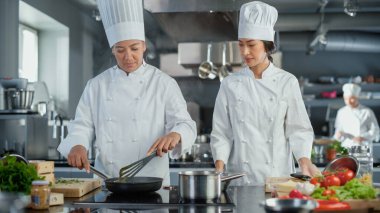 Restoran Mutfağı: Asya ve Kara Kadın Aşçıların Tabakları Hazırlama, Sebze Kesme, Kızartma Tavasında Karıştırma İçindekiler. İki