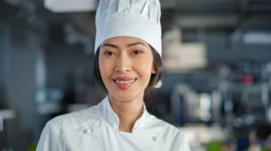 Dünyaca Ünlü Restoran: Modern Profesyonel Mutfakta Dönen ve Kamera ve Gülümseyen Asyalı Kadın Aşçının Portresi. Yemek pişirme
