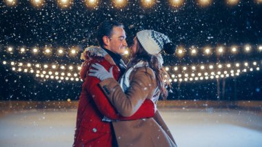 Romantik Kış Karlı Gecesi: Buz pateni yapan çift buz pateni pistinde eğleniyor. Çift Paten Erkek Arkadaşı ve Kız Arkadaşı Birbirine Aşık, Dans Ediyor