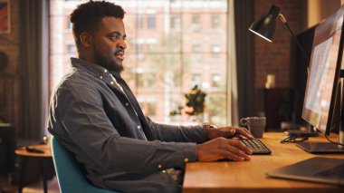 Sunny Stylish Apartmanında, Evden Masaüstü Bilgisayarında Çalışan Yakışıklı Afrikalı Amerikalı Adam. Yaratıcı Erkek Sosyal Medya Denetleme