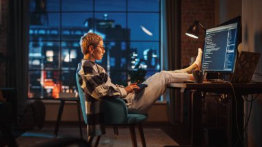 Genç Kadın, Akşamları Stylish Loft Apartmanında Bilgisayar Kodu Yazıyor. Yaratıcı Kadın Giysileri Giyen, Masada Ayaklarını Dinlendiren ve Kullanan