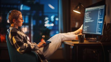 Genç Kadın, Akşamları Stylish Loft Apartmanında Bilgisayar Kodu Yazıyor. Yaratıcı Kadın Giysileri Giyen, Masada Ayaklarını Dinlendiren ve Kullanan