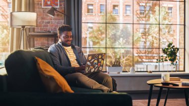 Sunny Stylish Apartmanında laptopta çalışan yakışıklı siyah adam. Yaratıcı Erkek Sosyal Medya Denetleme ve Tarama