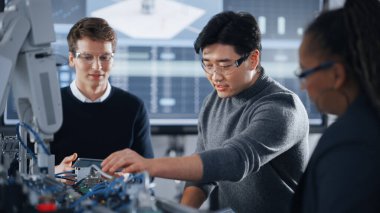 Asyalı Sınıf Arkadaşı ve Siyahi Öğretmenle Proje üzerinde çalışırken Erkek Öğrenci Robot El 'i Tutuyor ve Gösteriyor. Modern Teknolojiler