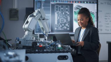 Siyah Geliştirici Dizüstü bilgisayarla çalışıyor, Robot Kolu için Kod Yazıyor. Uzmanların çalıştığı Bilgisayar Bilimi Araştırma Laboratuvarı. Yüksek Teknoloji Bilimi ve