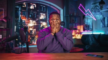 Dairesinden podcast kaydederken kendinden geçmiş genç siyahi adam mikrofona doğru konuşuyor. Mutlu Çoklu Etnik Erkek Kamerada Konuşuyor ve