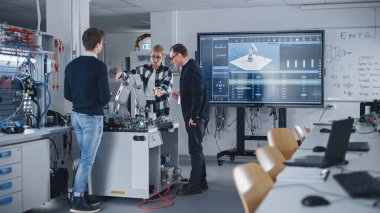 Erkek öğretmen, üniversitede ders sırasında zeki öğrencilerinin fikirlerini özenle dinliyor. İnsanlar El 'in Robotik Prototipini Tartışıyor