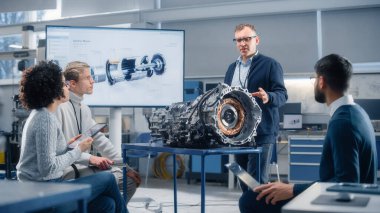 Çeşitli Mühendisler Ekibi, Araştırma Laboratuvarındaki Elektrikli Araç Motorunu Analiz Etmek için Laptop ve Tablet kullanıyor. Modern Endüstri 4 Sürdürülebilir Enerji