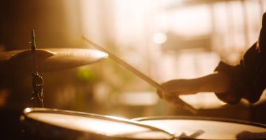 Close Up Cinematic Portrait of a Young Female Playing Drums, Using Cymbals in a Loft Music Rehearsal Studio Filled with Warm Sunset Light. Rock Band