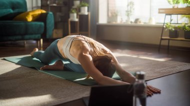 Athletic Young Female Exercising, Stretching and Doing Yoga while Watching Training Video on Laptop Computer. Beautiful Fit Woman in Sports Clothes