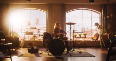 Young Female Playing Drums During a Band Rehearsal in a Loft Studio with Warm Sunlight at Daytime. Drummer Girl Practising Before a Live Concert on