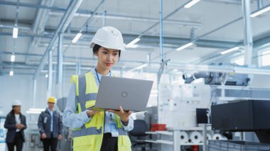 Portrait of a Happy Asian Female Engineer in Hard Hat Standing and Using Laptop Computer at Electronic Manufacturing Factory. Technician Working on