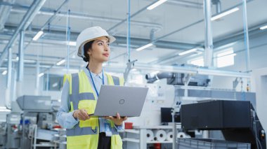 Portrait of a Happy Asian Female Engineer in Hard Hat Standing and Using Laptop Computer at Electronic Manufacturing Factory. Technician Thinking