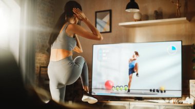 Home Training: Beautiful Girl Training with Personal Trainer via Online Video App. Authentic Athletic Woman Using Workout Service in Fitness Streaming
