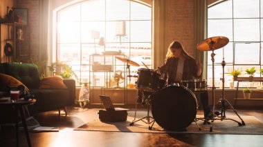 Young Female Playing Drums During a Band Rehearsal in a Loft Studio with Warm Sunlight at Daytime. Drummer Girl Practising Before a Live Concert on